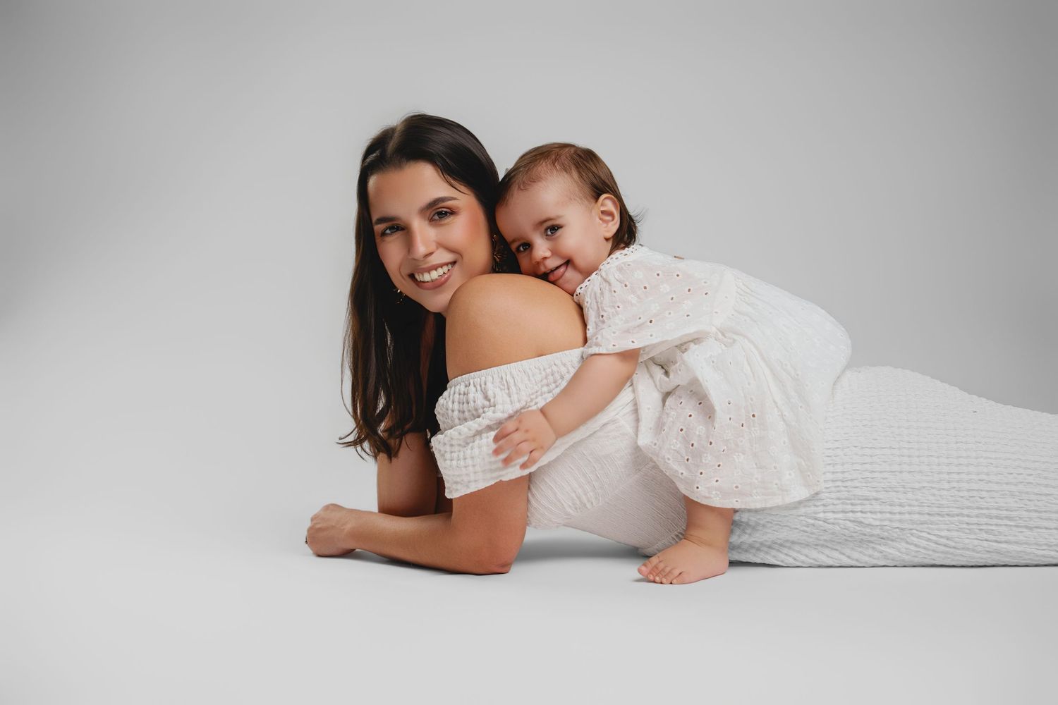 Intimate lifestyle portrait session showing tender moments on grey backdrop.