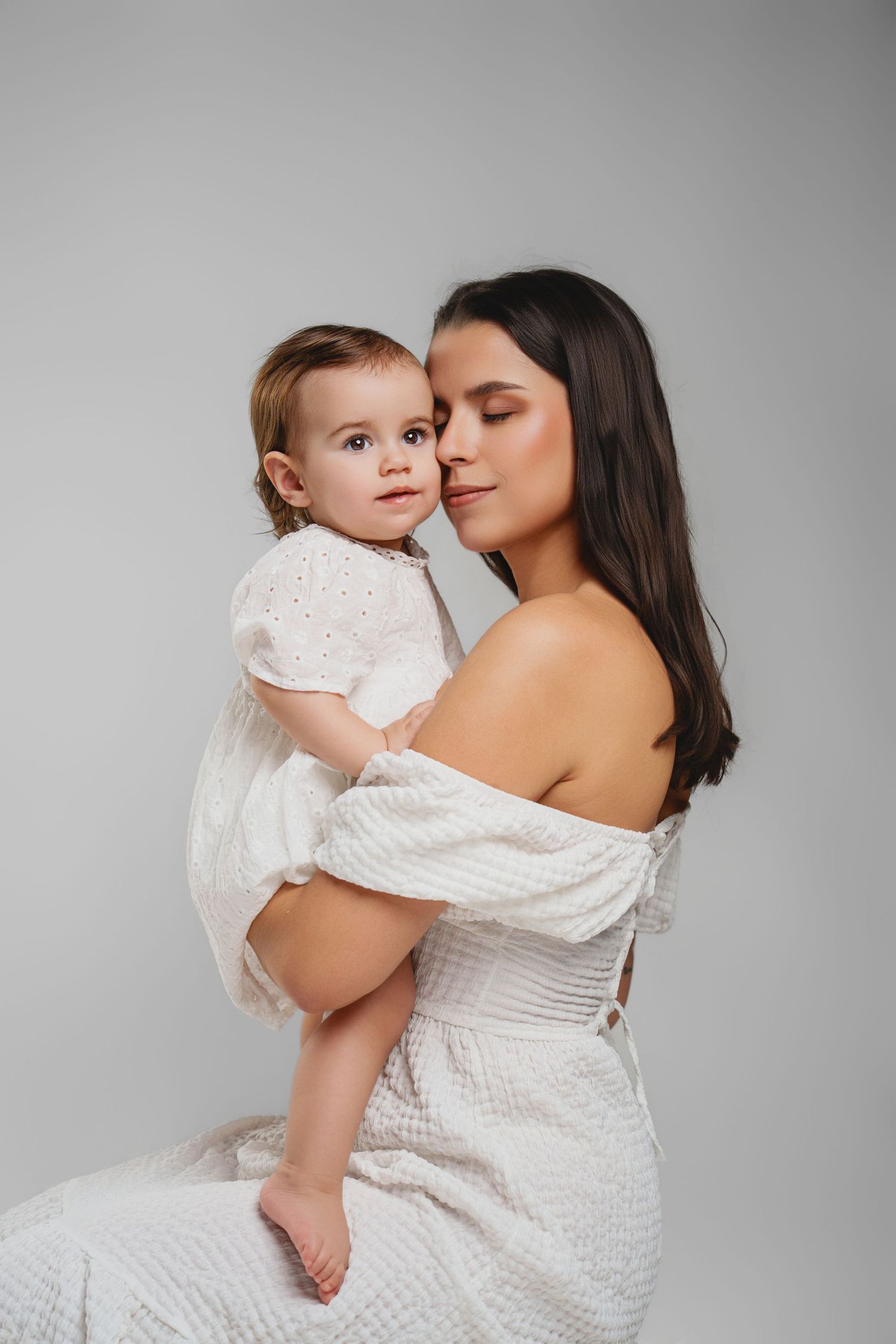 Emotional portrait session featuring white textured dress against minimalist grey background.