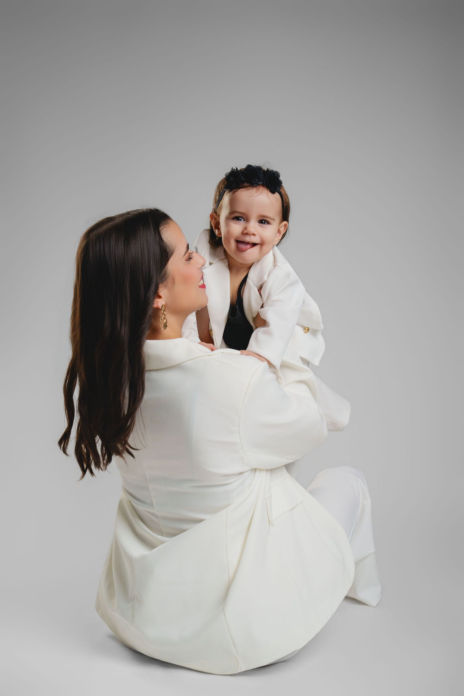 Joyful studio portraits showing playful interaction against light grey background.