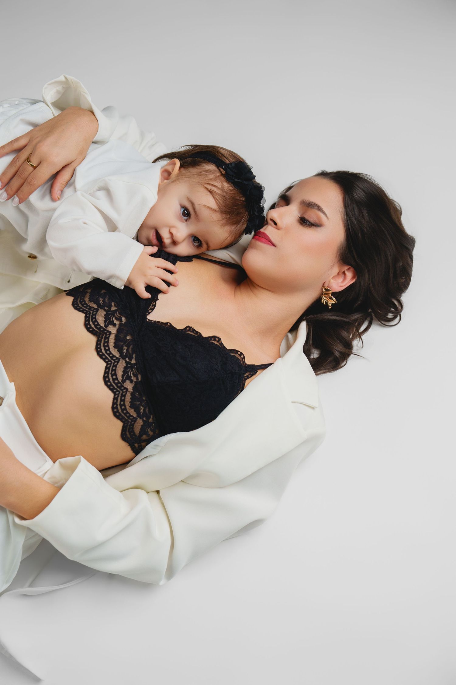 Intimate lifestyle portraits featuring white blazer and black lace top on grey backdrop.