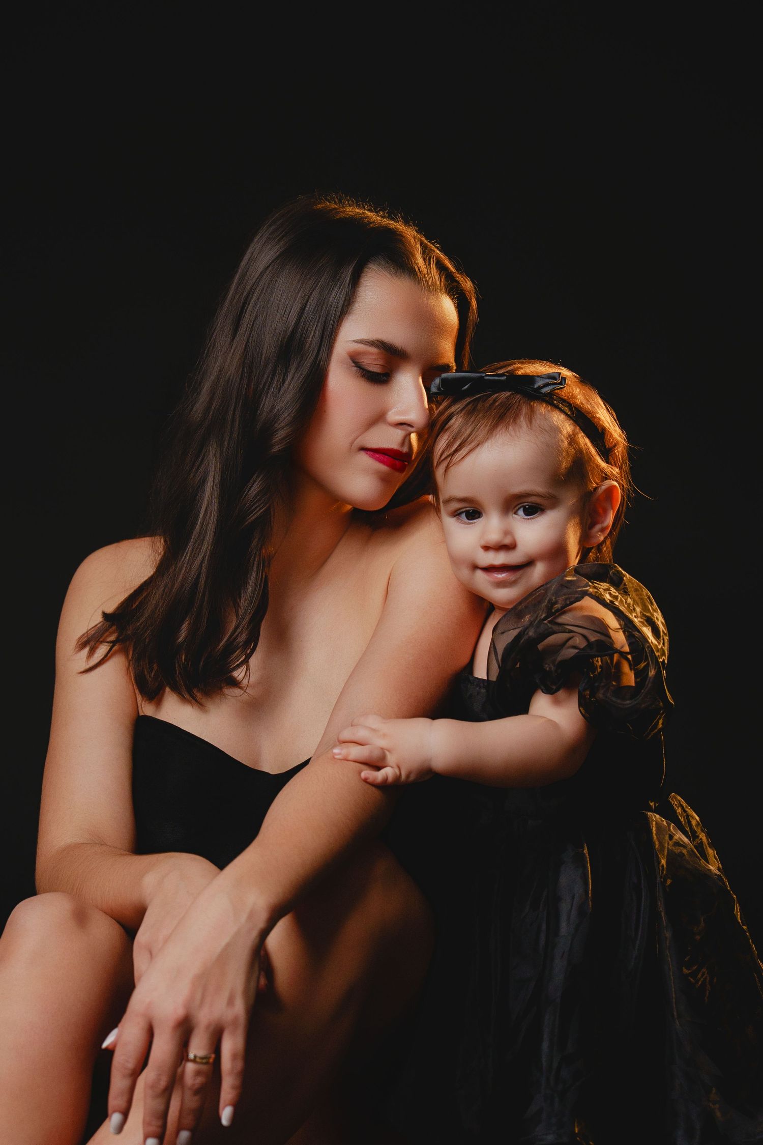 Moody studio portraits with dramatic side lighting against black background.
