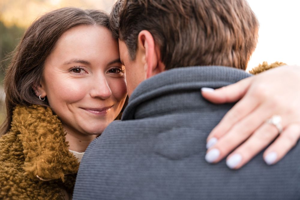 A tender embrace between a couple outdoors with a mustard yellow scarf visible in the frame.