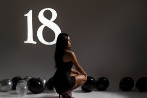 Silhouetted figure in black dress poses against white backdrop in artistic fashion photoshoot series.
