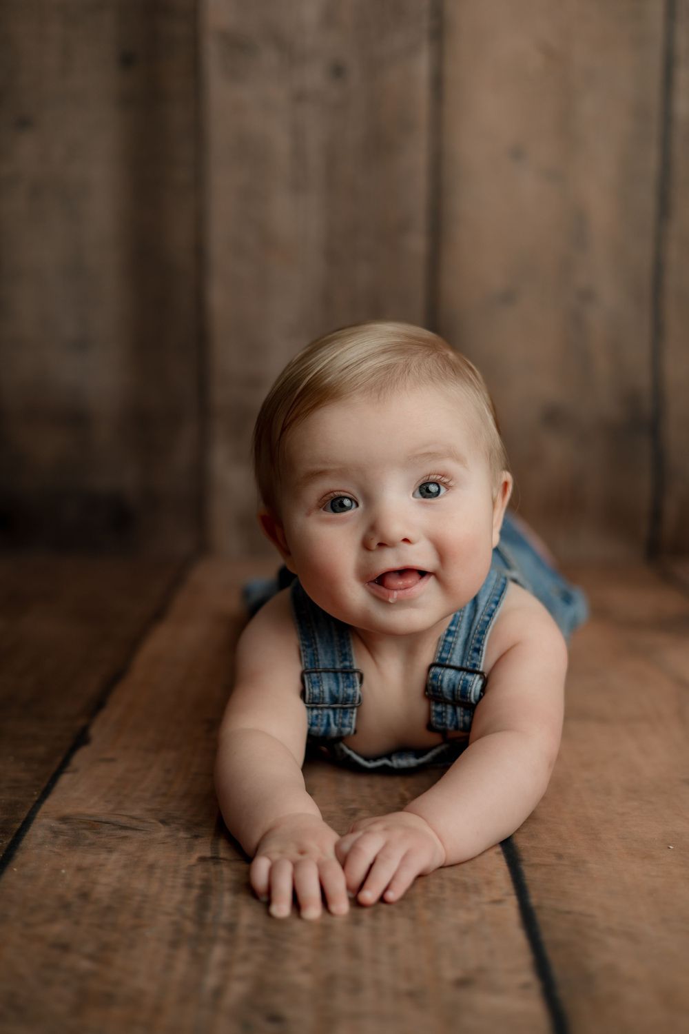 Studio portrait on wooden floor wearing denim overalls.