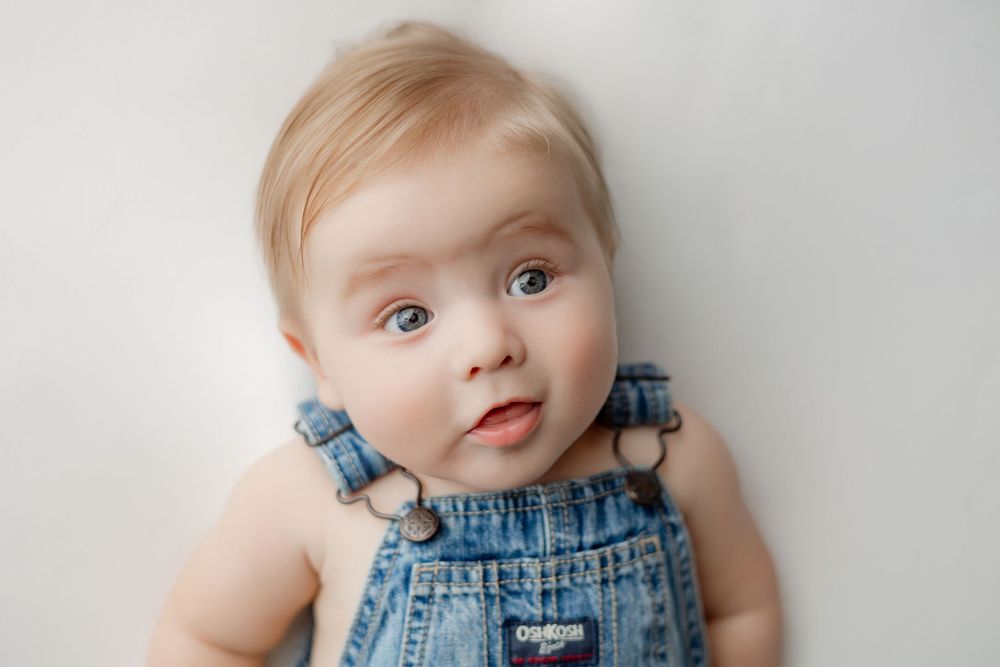 Portrait against white background wearing blue denim overalls.