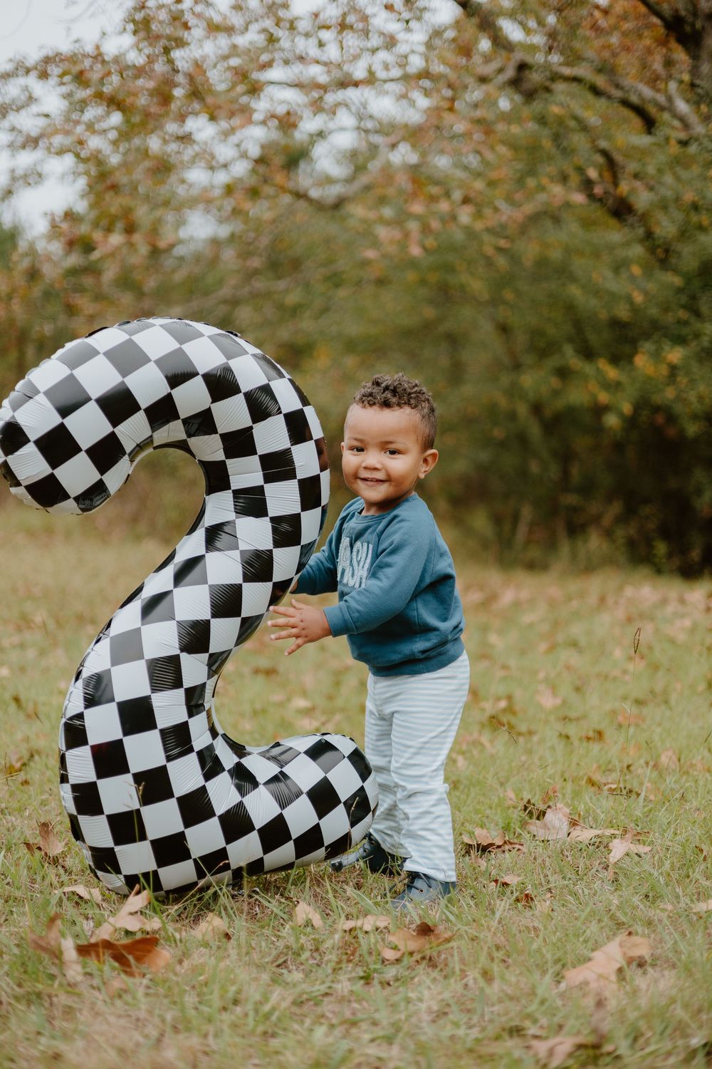 A checkered racing-themed number 2 prop displayed in an outdoor fall setting.