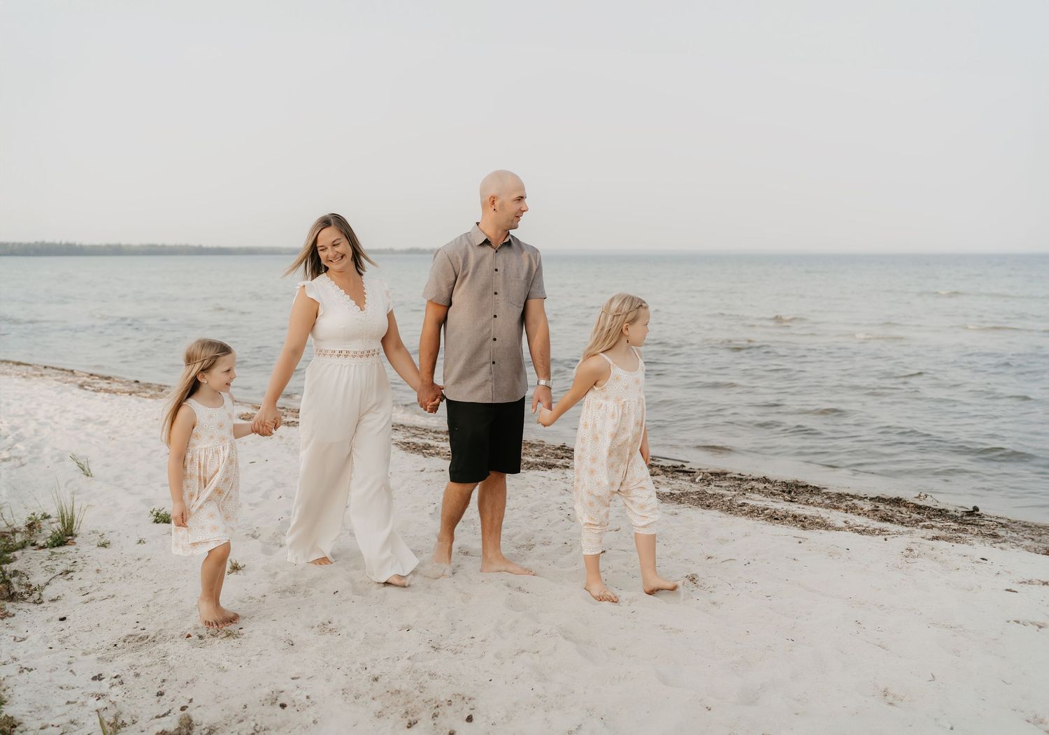 Family walking and playing together on sandy beach during golden hour.