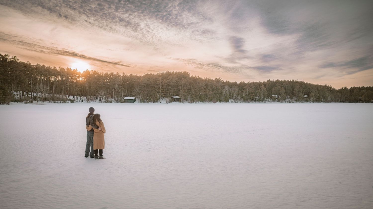 Couple embracing in playful pose at sunset in grassy field.