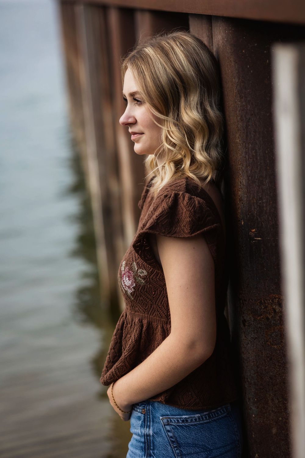 Soft waterfront portrait with wooden pier posts creating leading lines.