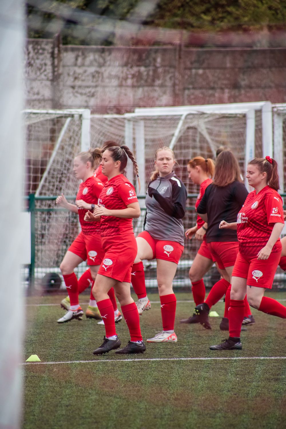 Redditch Utd Women warming up before a football game, shot through the net of the goal
