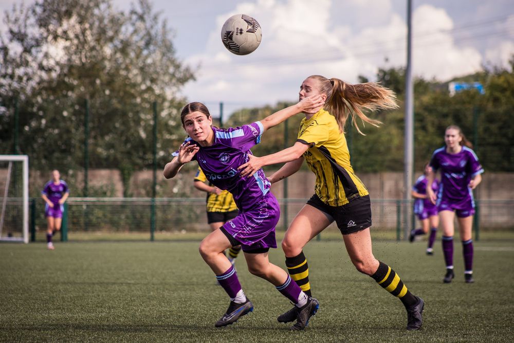 Female football players in pursuit of the ball mid football game