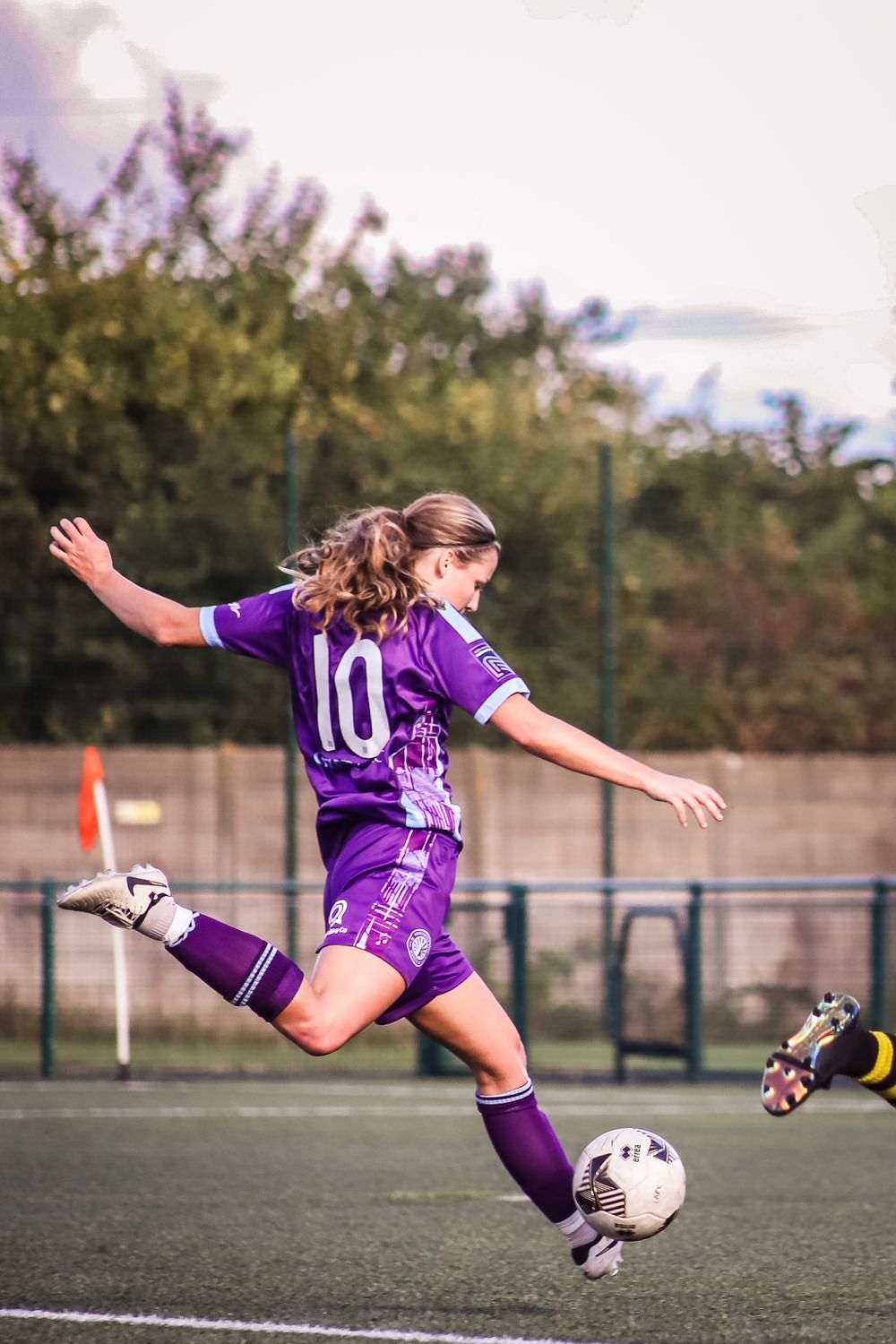 Image taken from behind of a female footballer from Worcester City Women's First team about to kick a ball wearing purple
