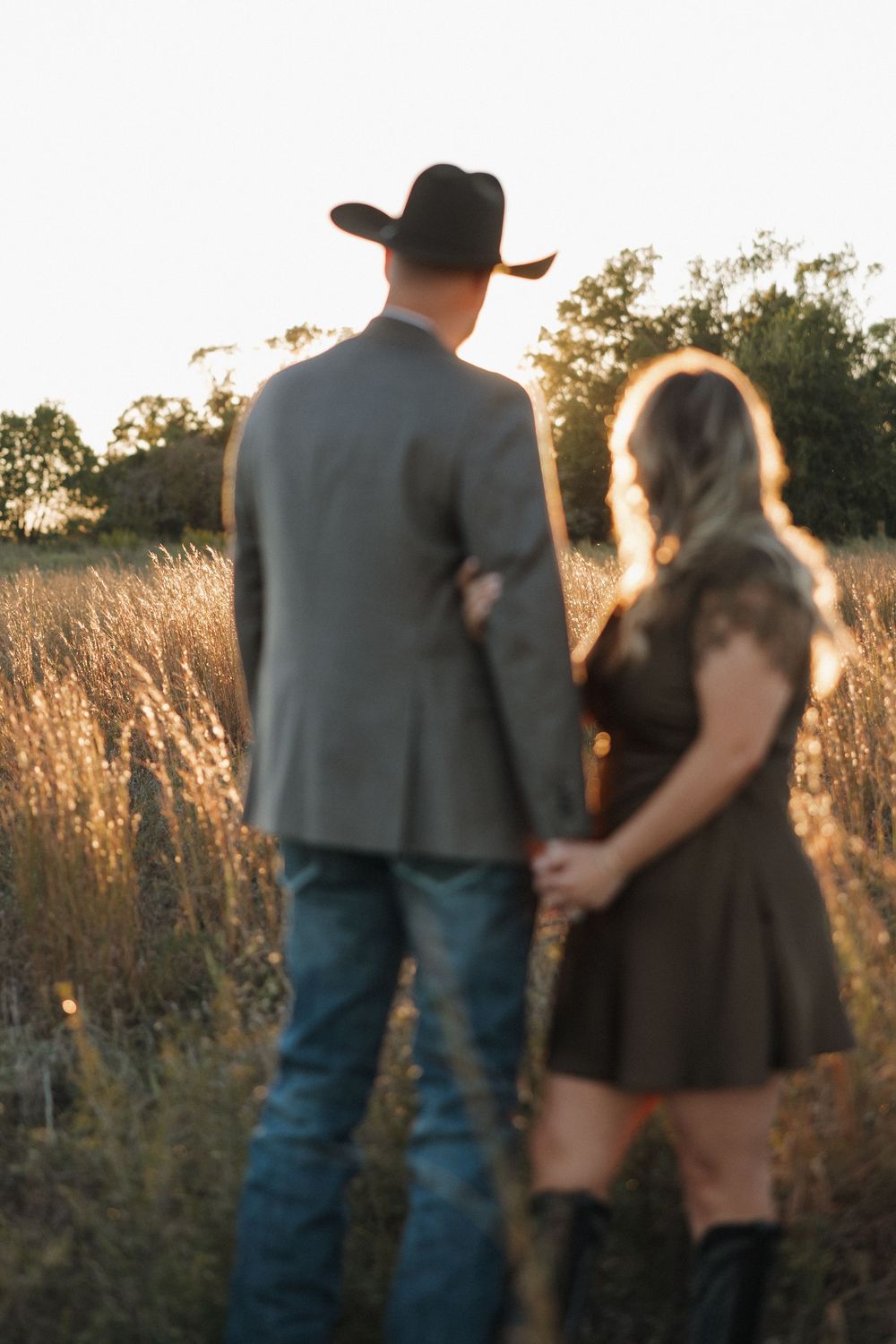 A couple embraces in a golden field at sunset, creating a romantic silhouette against the warm evening light.