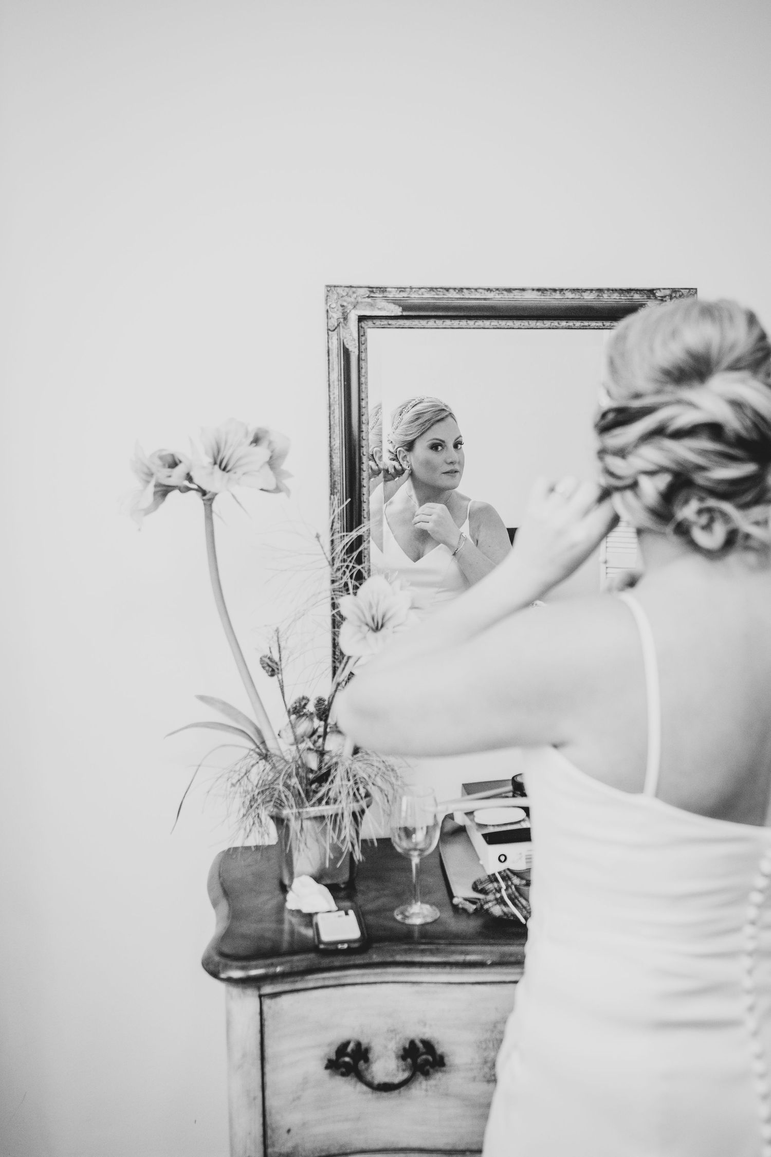 Classic bridal portrait, B+W, putting earrings in the reflection of a framed mirror.