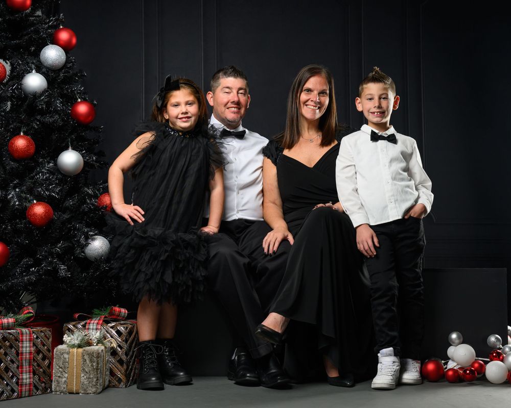 Holiday themed indoor portrait session with Christmas decorations and formal attire.