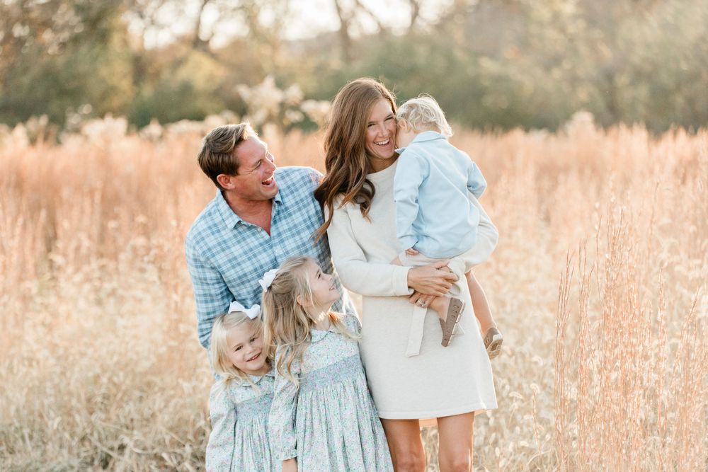 A loving family shares joyful moments together in a golden wheat field during sunset.