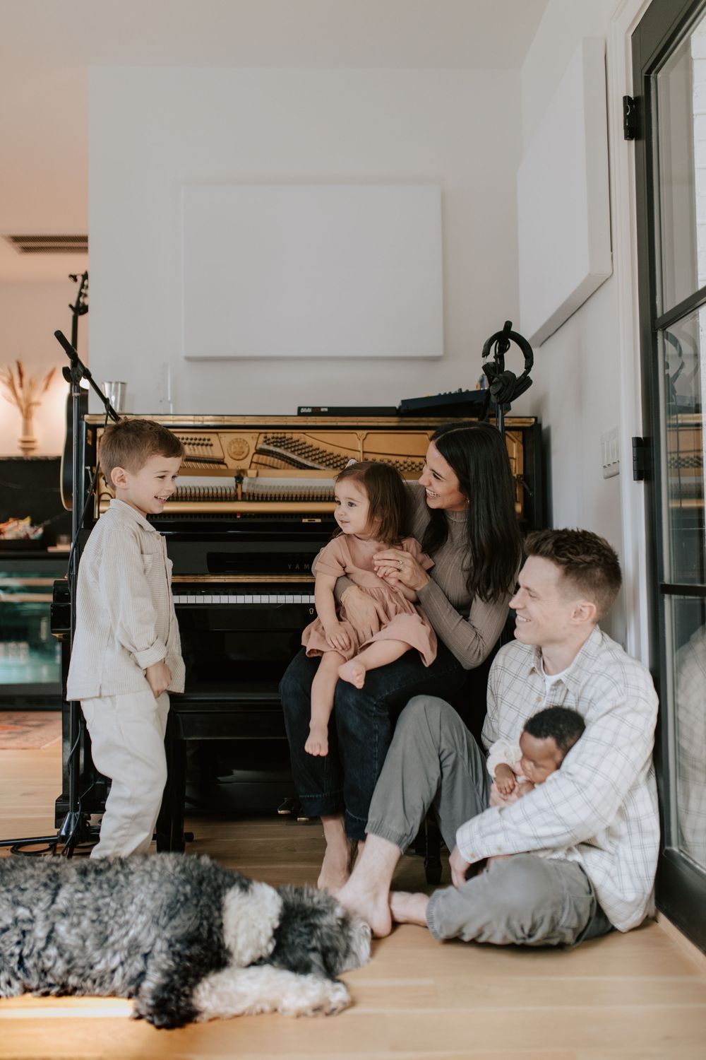 Family sitting together with their pets on a white floor during an indoor lifestyle photoshoot.