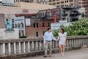 Couple standing on urban rooftop terrace with city buildings in background.