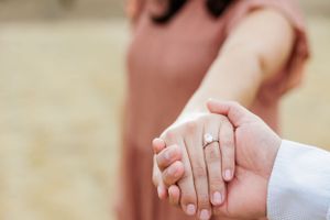Close-up shot of hands with engagement ring showing romantic moment.