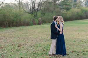 Romantic couple in formal wear share intimate moment in open field.