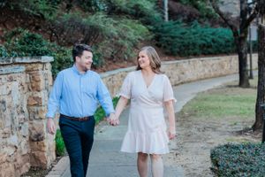 Couple walking along stone wall path surrounded by greenery.