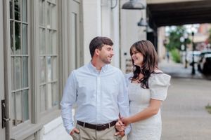 Couple in coordinated white and blue outfits walking along storefront.