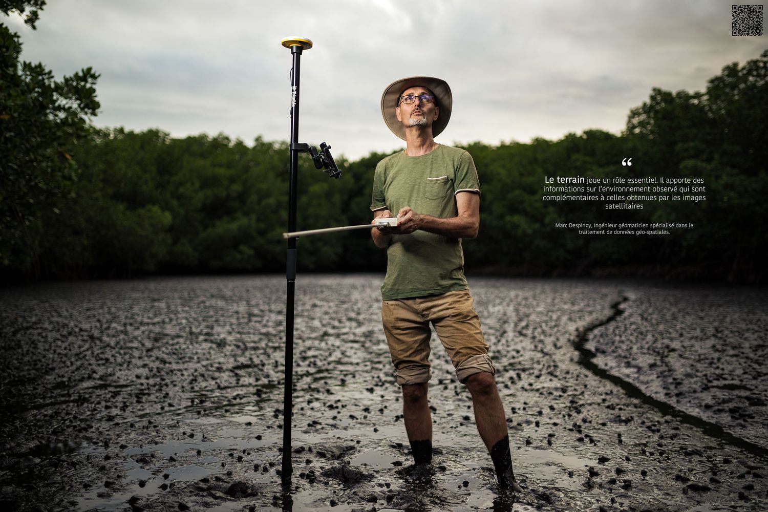 Photographie d'un ingénieur en télédétection à Nouméa au milieu d'une vasière, entouré de mangroves, tenant un appareil scientifique