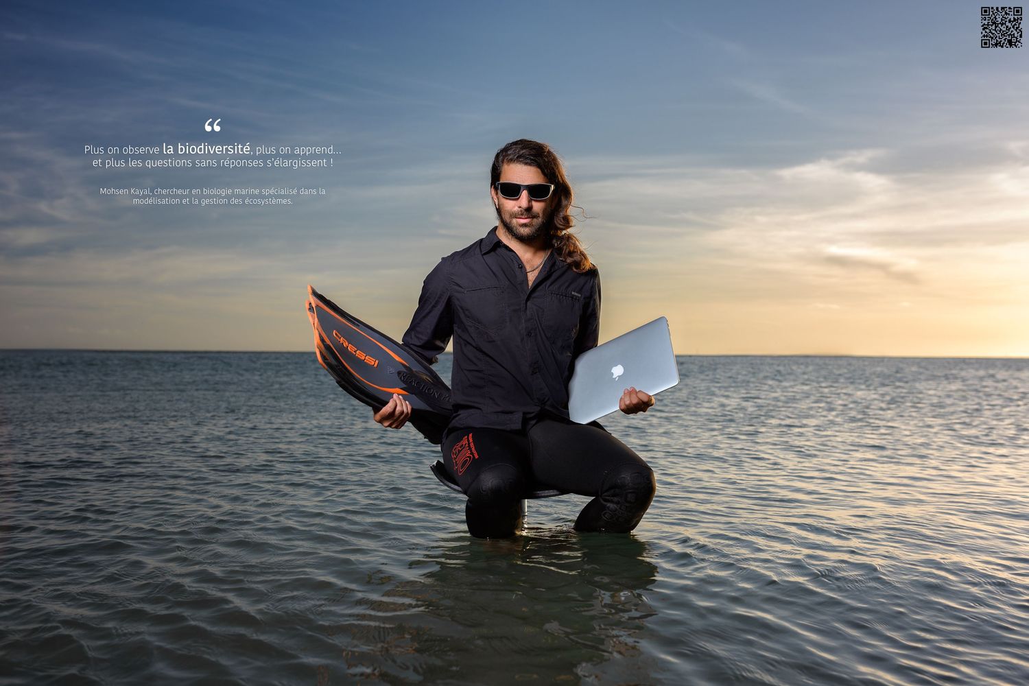 Chercheur tenant une paire de palmes et un ordinateur portable, assis sur un tabouret en mer, photographie conceptuelle et scientifique