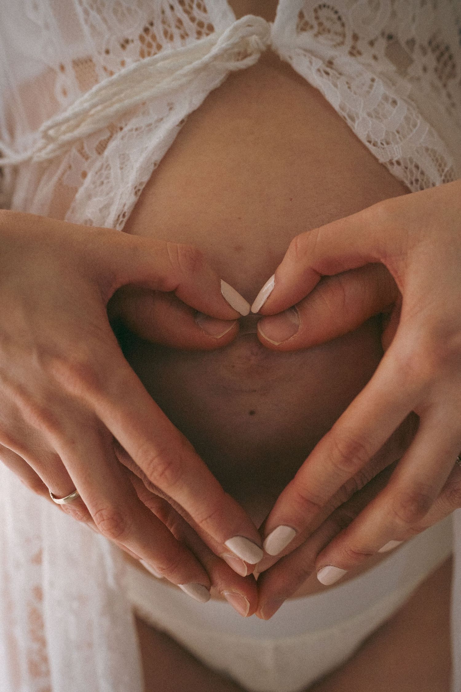 Close-up shots of hands forming a heart shape over a pregnant belly.