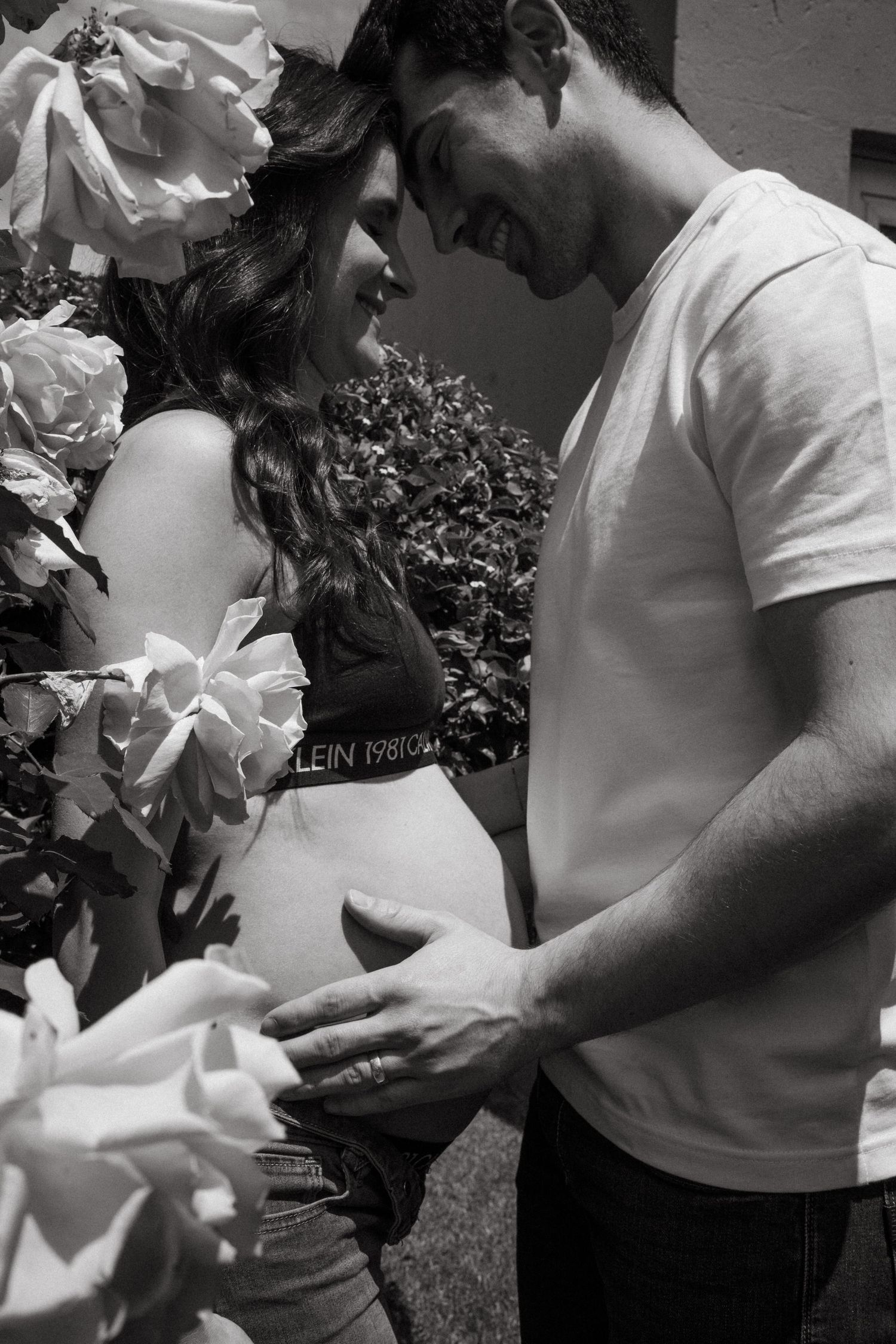 Black and white maternity photo with roses and intimate pose.