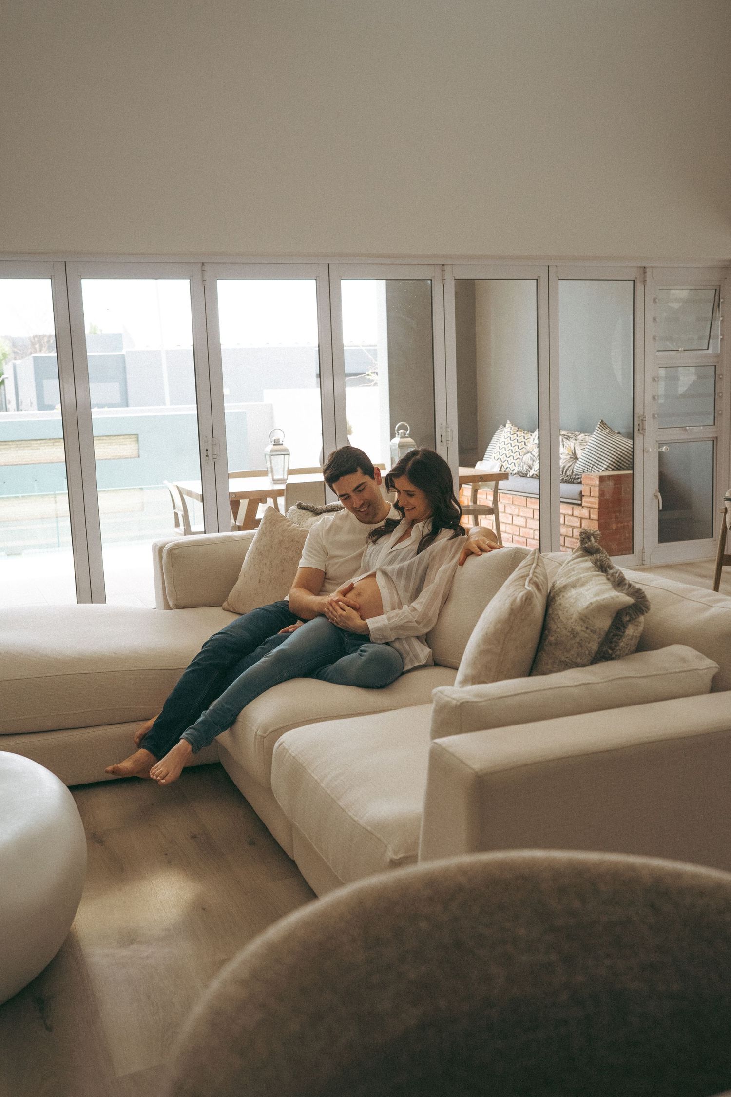 Couple lounging together on comfortable sectional sofa near large windows with ocean view.