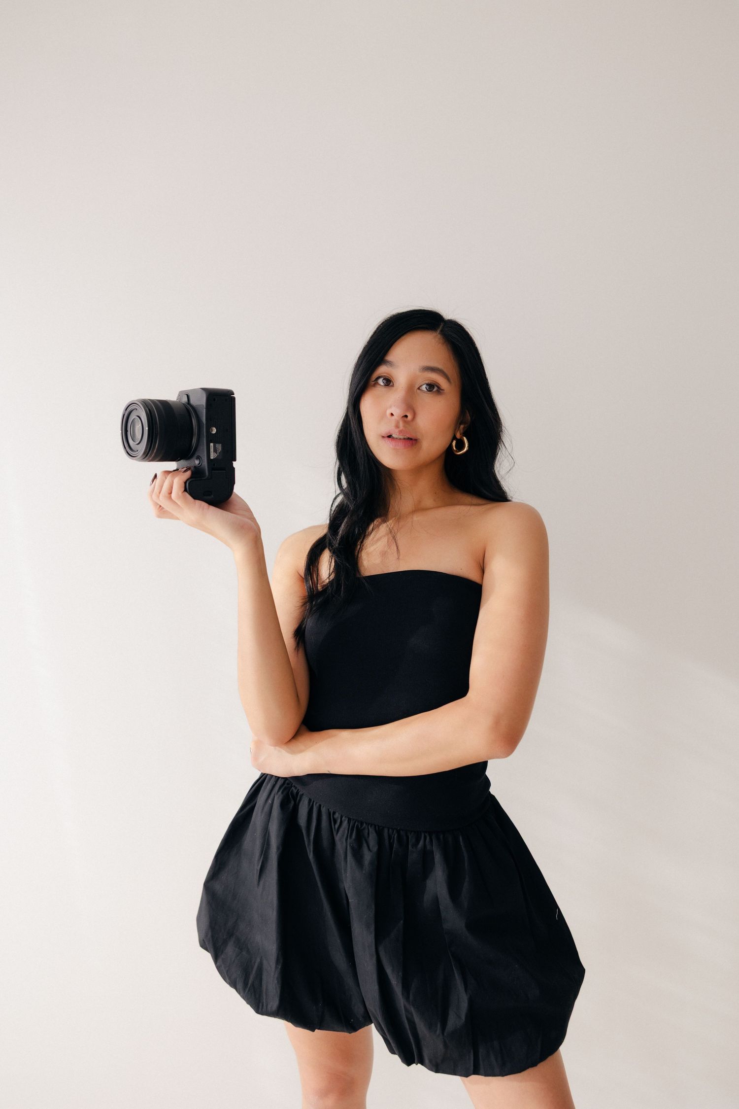Creative self-portrait series with camera against white background in black outfit.