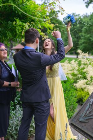 A wedding couple standing before the justice of the peace in an outdoor park garden erupt with joy.