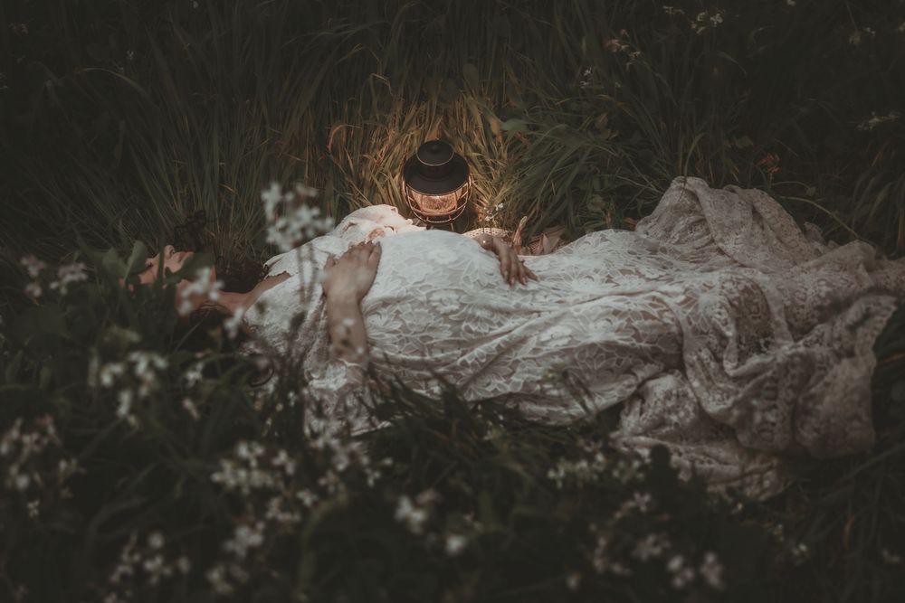 A couple poses for wedding photos in a dreamy garden setting with white floral arrangements and natural greenery.