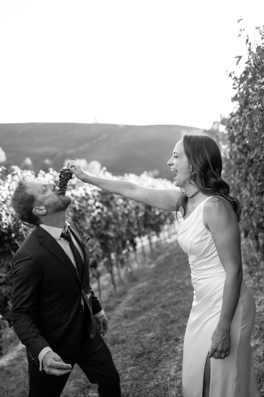 Black and white photo series of a couple in wedding attire posing playfully in a vineyard in Italy
