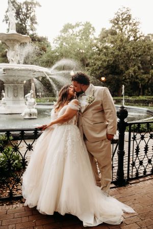 Wedding couple posing by a grand fountain at a luxury destination venue by Branson, MO Photographer L. Ballenger Photography.