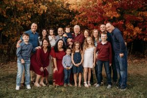 Large extended family reunion portrait in front of vibrant red fall foliage in Branson, Missouri by L. Ballenger Photography.
