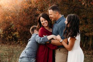 Emotional family hug in the autumn woods during a sunset photo session in the Ozark Mountains with L. Ballenger Photography.