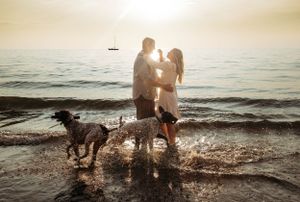 Couple and their two dogs playing in the water at Table Rock Lake during a sunset photoshoot with L. Ballenger Photography.