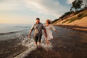 Couple running through the water at Table Rock Lake for an adventurous engagement photo session in Branson, Missouri.