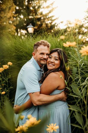 Couple embracing in a lush garden during a summer engagement photo session in Branson, MO by L. Ballenger Photography.
