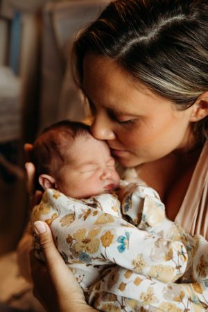 Intimate motherhood photo session in Branson featuring a mother kissing her newborn baby, captured by L. Ballenger Photography.
