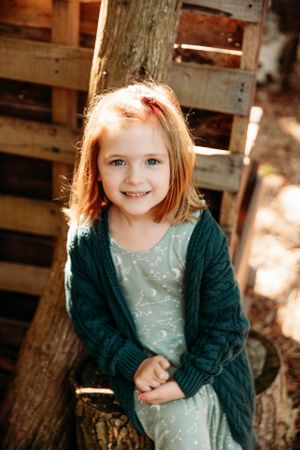 Young girl in a green dress smiling outdoors during a family photo session in Branson, MO by L. Ballenger Photography.