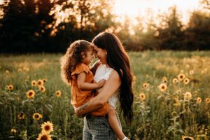 Mother and child hugging in a sunflower field during a late summer photo session in Branson by L. Ballenger Photography.
