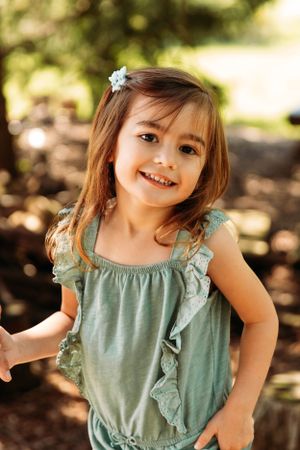 Close-up portrait of a smiling young girl in a sage green dress during a family photoshoot in Branson, Missouri by L. Ballenger Photography.