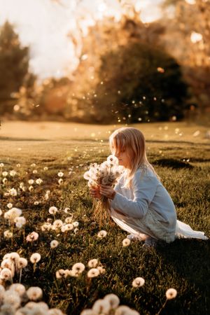 Toddler sitting in a field of white flowers at sunset for a whimsical photo session by L. Ballenger Photography.