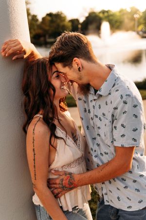 Romantic couple embracing against a white pillar for an engagement photo session in Branson, MO by L. Ballenger Photography.