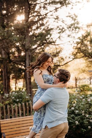 Man lifting a woman in a blue dress during a playful lifestyle photo session in Branson, MO by L. Ballenger Photography.