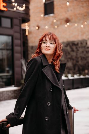 Urban-style senior portrait of a girl in a black coat in Downtown Branson, captured by L. Ballenger Photography.