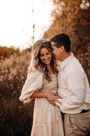 Romantic couple embracing in a sun-drenched field for a golden hour photo session in the Ozarks with L. Ballenger Photography.